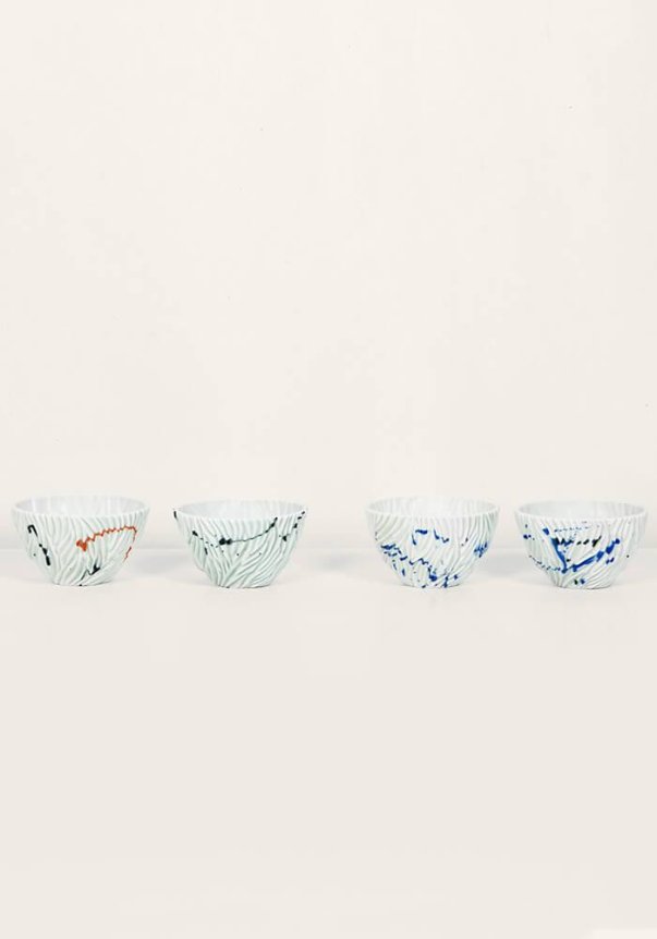 Four porcelain bowls with wavy patterns in various colors on a plain white background.
