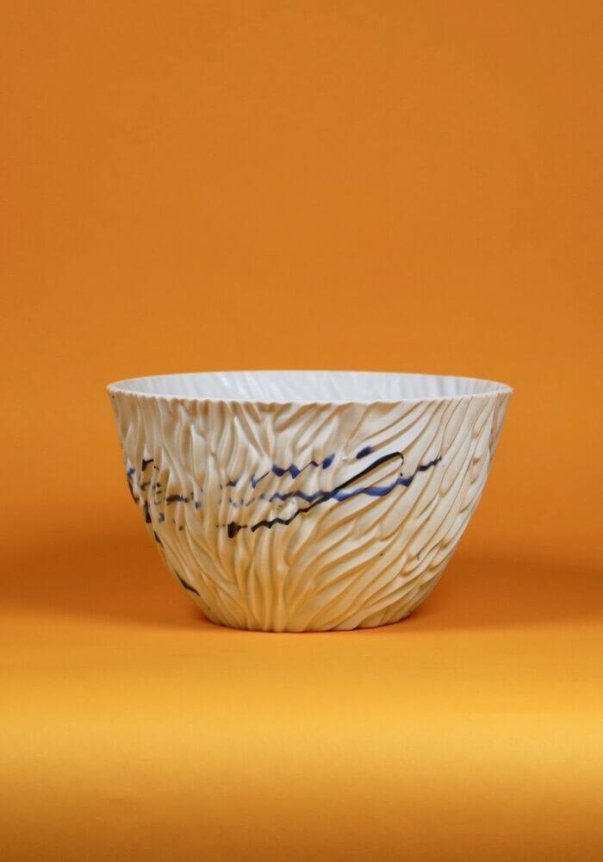 A textured ceramic bowl with blue abstract patterns against an orange background.