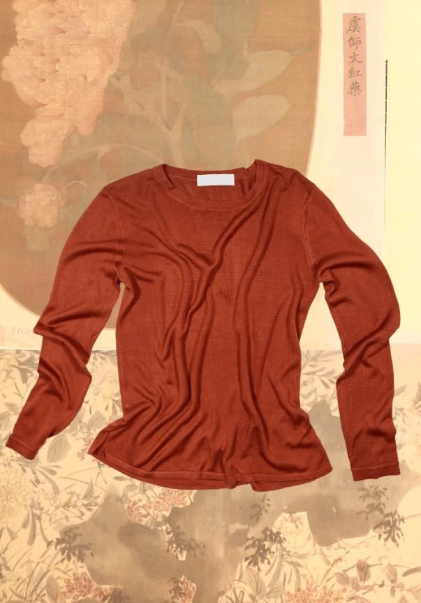 A rust-colored long-sleeve, fitted knit top with a ribbed texture, set against a floral and abstract background.