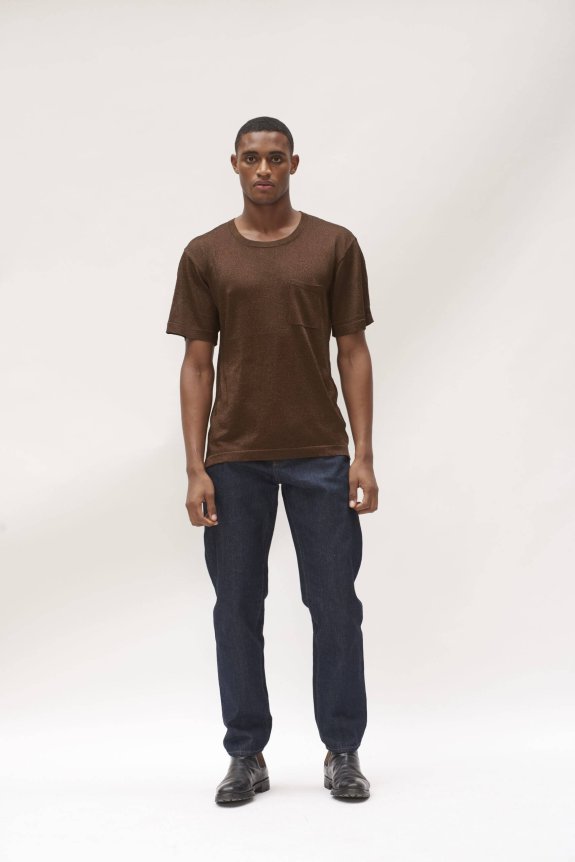 A model wearing a brown, casual short-sleeve shirt with a slightly fitted style, paired with dark blue jeans and black leather shoes.