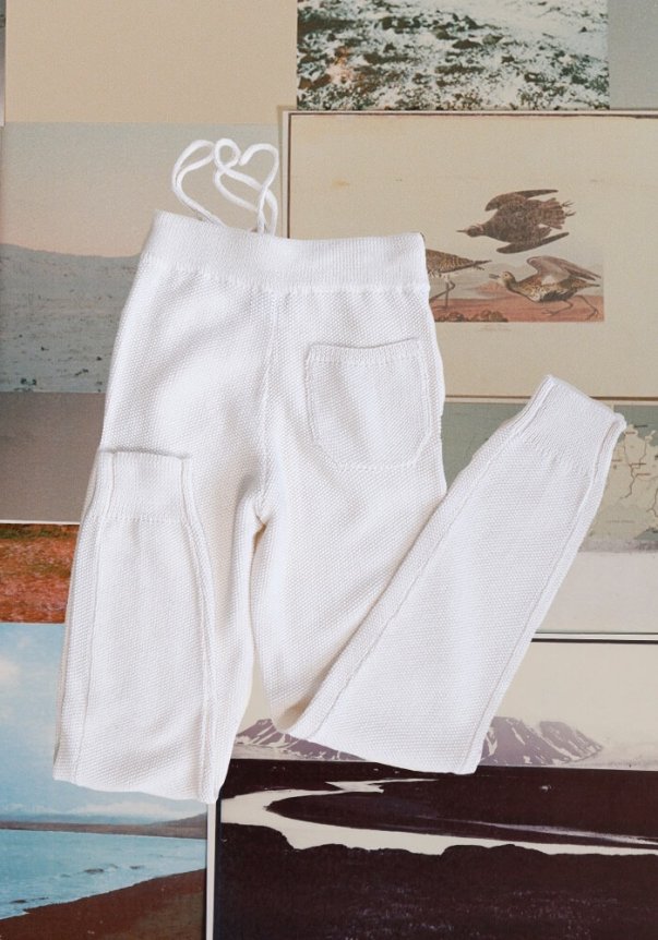 White knit pants with a drawstring waist, pocket detailing, and surrounded by nature-themed illustrations in the background.