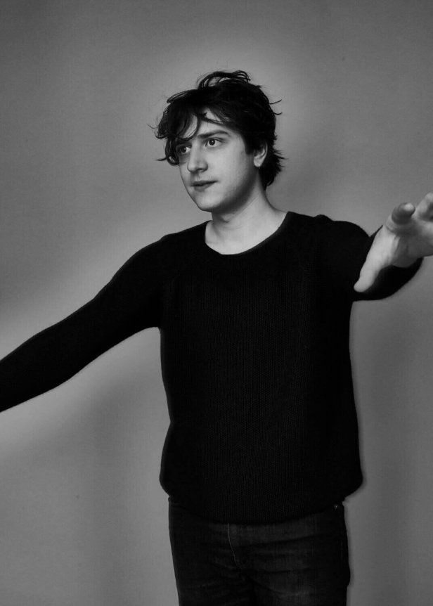 A black, long-sleeved, slightly loose-fitting sweater made of knit material worn by a person.