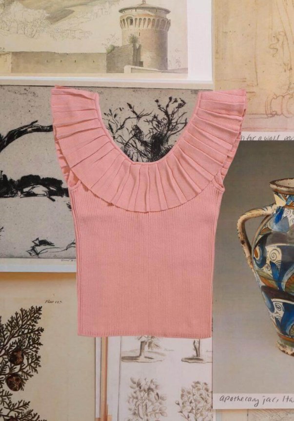 A pink ribbed sleeveless top with a wide pleated ruffle collar, set against a collage of art prints.