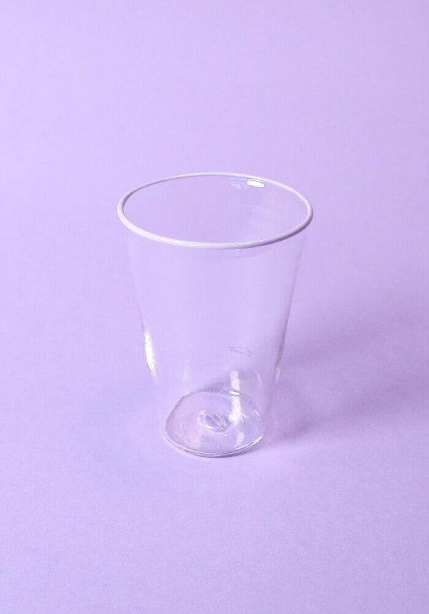 A clear plastic cup is placed against a pastel purple background.