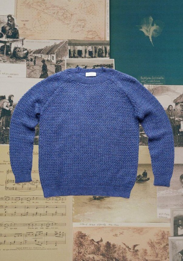 A charcoal gray, long-sleeve wool sweater on a backdrop of vintage botanical illustrations.