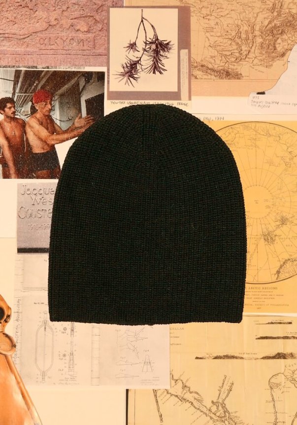 A burgundy knit beanie with a textured pattern is set against a backdrop of vintage maps and botanical illustrations.