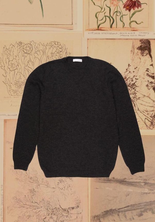 A lavender knit crewneck sweater with a relaxed fit, displayed against a backdrop of vintage botanical and bird sketches.
