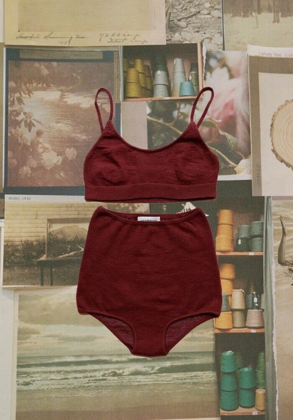 A burgundy two-piece underwear set featuring a soft, seamless bralette and high-waisted briefs, laid on a background of vintage photographs and colorful thread spools.