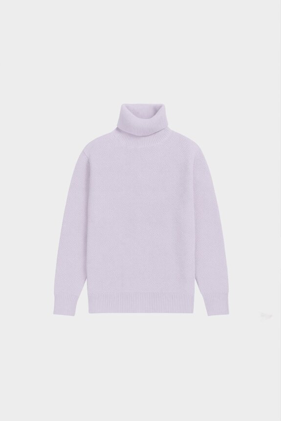 A lavender knit turtleneck sweater with a relaxed fit is displayed against a collage of icy and abstract background images.