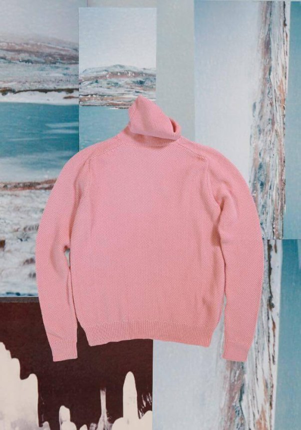 A pink knitted turtleneck sweater with a relaxed fit, displayed against a collage of abstract landscapes.