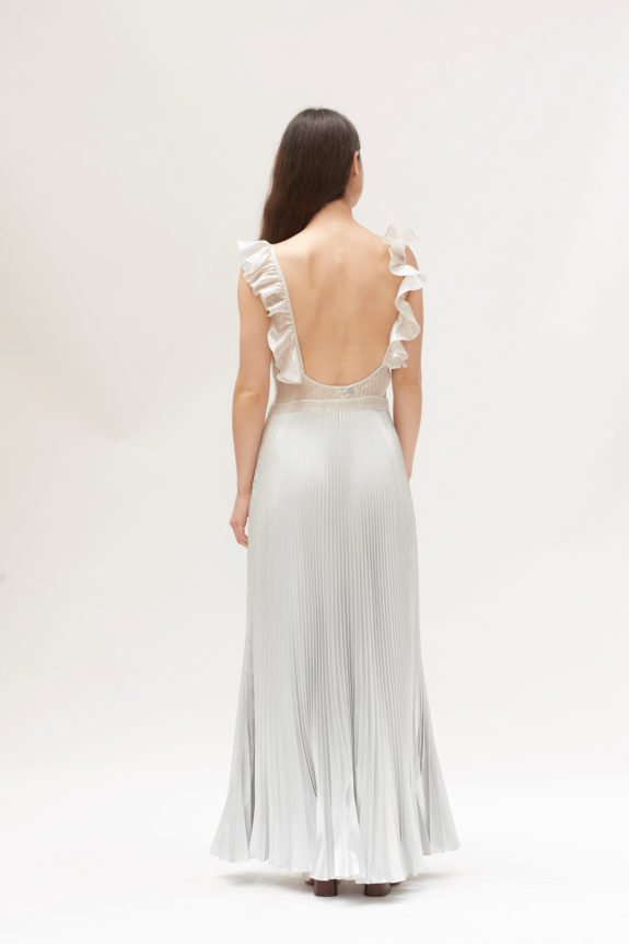 A silver, backless evening gown with pleated skirt and ruffled shoulder straps.