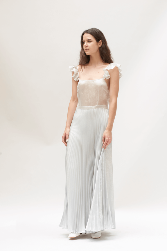 A silver pleated maxi dress with ruffled straps and a fitted, semi-sheer bodice.