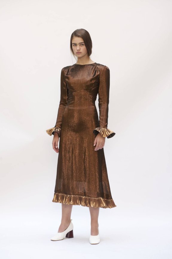 A metallic copper long-sleeved dress with ruffled cuffs and hem, featuring a fitted silhouette and shiny texture.