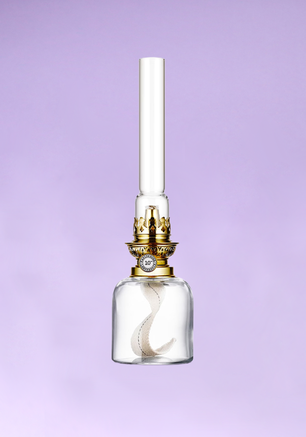 A vintage-style glass oil lamp with a gold crown and a long, clear chimney against a soft purple background.