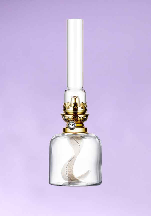 A vintage-style glass oil lamp with a golden metal burner and a tall, clear chimney set against a purple background.