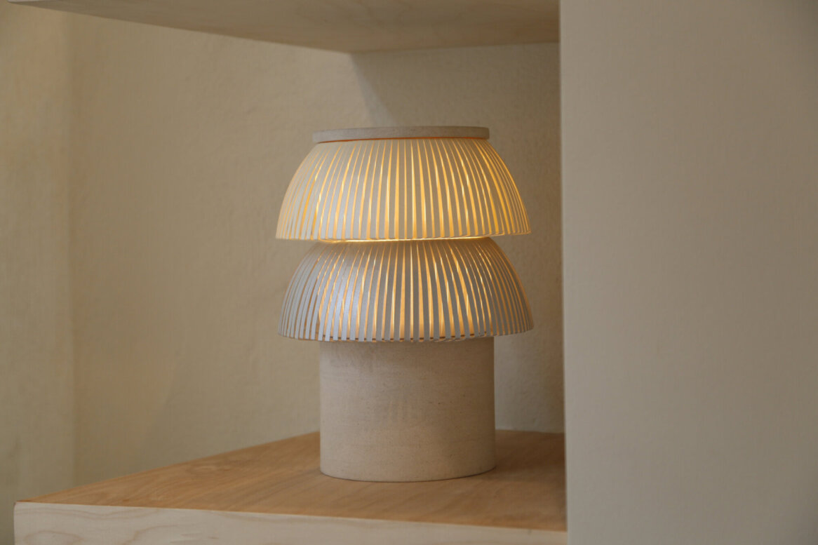 A modern table lamp with two layered, perforated shades emitting a warm glow.