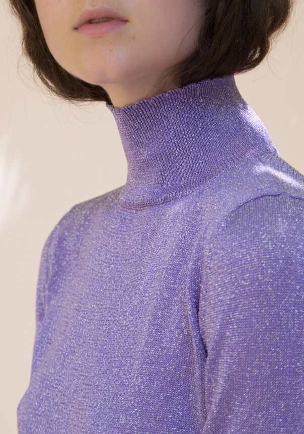 A person wearing a sparkly purple turtleneck sweater.