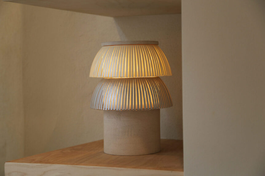 Hesperios modular paper lighting with pleated sculptural table lamp with stone base.