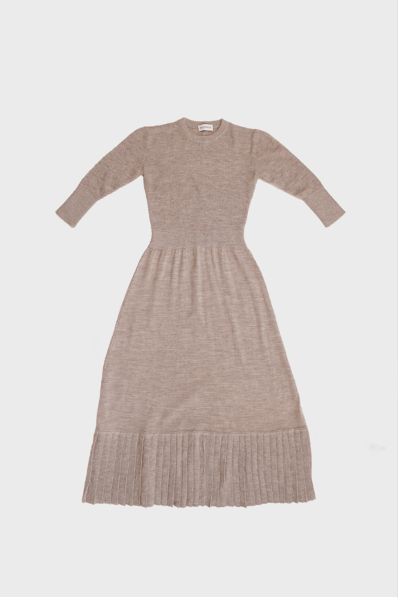 A long-sleeved, light brown knit dress with a gathered waist and pleated hem.