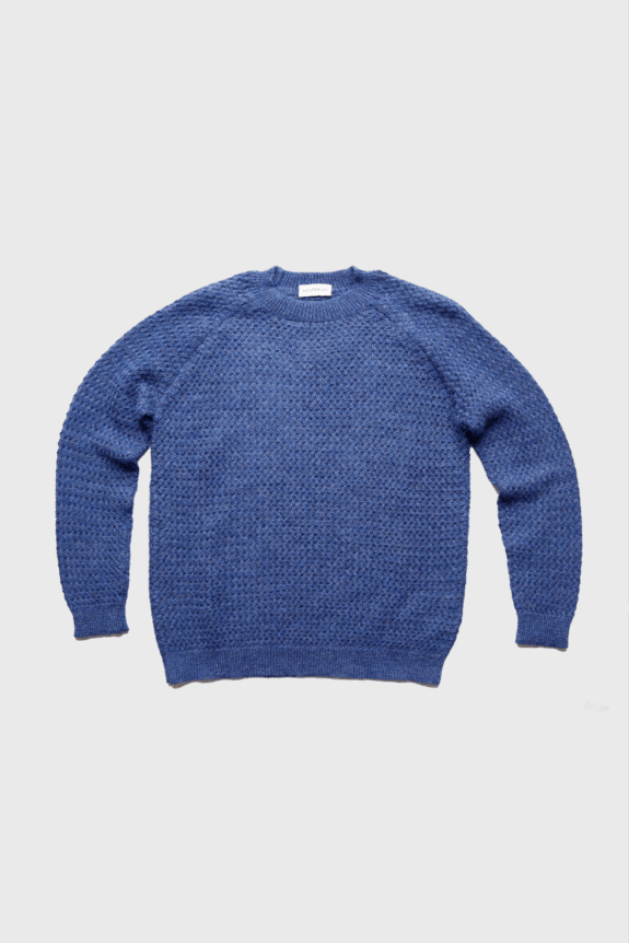 A blue textured sweater laid flat on a white background.