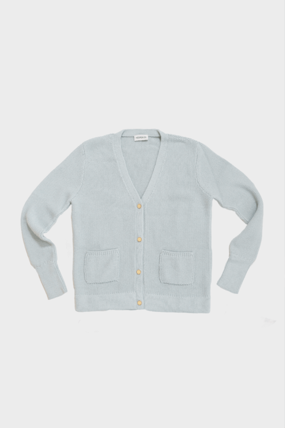 Light blue cardigan with pockets and buttons, laid flat.