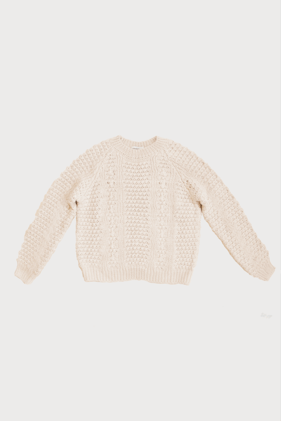 A cream-colored knitted sweater with a textured pattern.