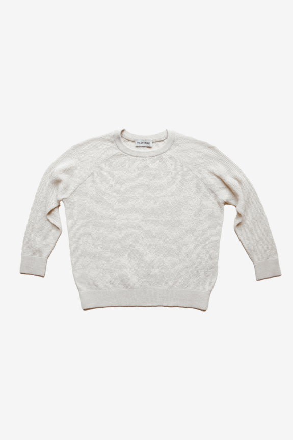A white textured knit sweater with long sleeves and a crew neck.